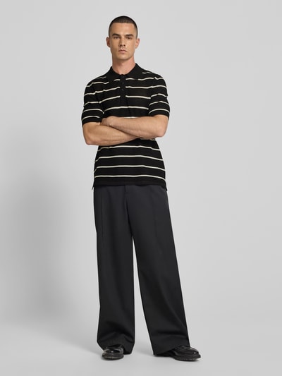 Männermodel trägt Poloshirt aus Viskose-Mix von Filippa K in Schwarz mit cremefarbenen Streifen, relaxed Fit, Ganzkörperansicht von vorne.