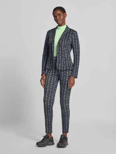 Frauenmodel trägt Slim Fit Blazer mit Logo-Detail von Marc Cain, dunkles Muster, Reverskragen, elastischer Material-Mix, Ganzkörperansicht von vorne.