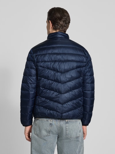 Mężczyzna model nosi Regular Fit Steppjacke mit Stehkragen od Tom Tailor w kolorze granatowym, gładka faktura, długie rękawy, pikowana, elastyczne wykończenia, boczne kieszenie na suwak, widoczny label patch, widok całej sylwetki od tyłu.