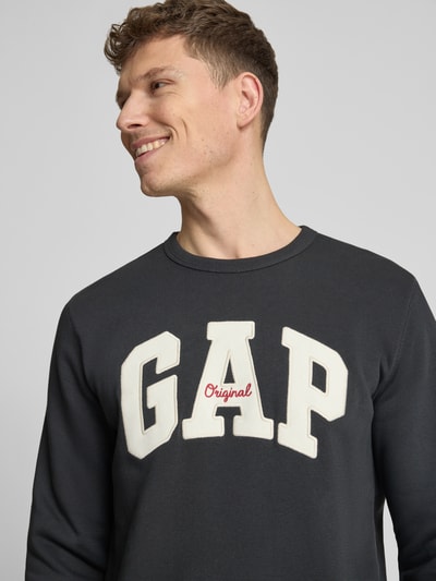 Männermodel trägt Sweatshirt mit Logo und Rundhalsausschnitt van GAP in zwart katoenmix, regular fit, logoprint, Nahaufnahme Oberkörper.
