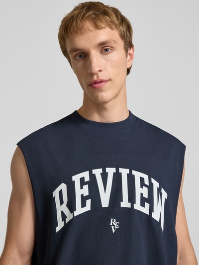 Männermodel trägt Tanktop mit Logo-Print von REVIEW in Dunkelblau, Reine Baumwolle, Gerader-Schnitt, Rundhalsausschnitt, Nahaufnahme Oberkörper.