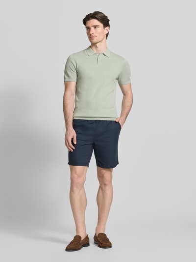Männermodel trägt Slim Fit Poloshirt in Strick-Optik Modell 'TRITON' von Drykorn, reine Baumwolle, Polokragen, Ganzkörperansicht von vorne