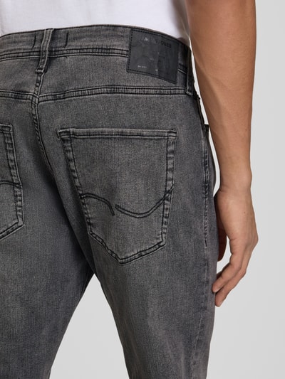 Mężczyznamodel nosi Slim Fit Jeans mit Lyocell-Anteil Model 'Clark' od JACK & JONES, mieszanka bawełny i lyocellu, 5 kieszeni, zapięcie na guzik i zamek błyskawiczny, szara tekstura, detal tylnej kieszeni, Długość wewnętrzna nogawki w rozmiarze 32/32: 78 cm, Szerokość w rozmiarze 32/32: 34 cm, zbliżenie tylnej części.