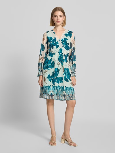 Frauenmodel trägt Knielanges Kleid im Allover-Look Modell 'Ja44milaa' von ZABAIONE mit blauen und beigen Blumen, Chiffon, A-Linie, V-Ausschnitt, Wickel-Optik, Ganzkörperansicht von vorne.