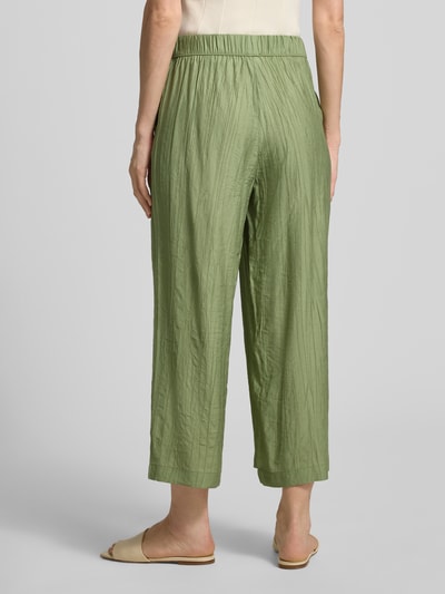 Frauenmodel trägt grüne Wide Leg Culotte aus Viskose-Mix von s.Oliver RED LABEL mit Crêpe-Struktur, Ganzkörperansicht Rückansicht.