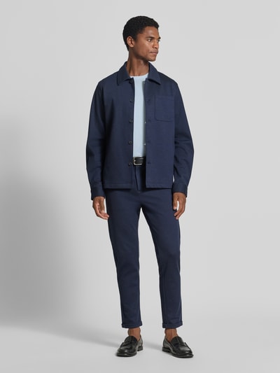 Männermodel trägt Slim Fit Hemdjacke mit Viskose-Anteil von Lindbergh in Dunkelblau, glatte Textur, Ganzkörperansicht von vorne. Herren Hemdjacke, elastischer Material-Mix, Umlegekragen, Knopfleiste, Brust- und Eingrifftaschen, Rückenlänge 70 cm bei Größe M.
