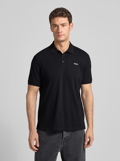 Männermodel trägt Regular Fit Poloshirt aus reiner Baumwolle Modell 'DONOS222' von HUGO, Optik: Unifarben, Piqué, Ganzkörperansicht von vorne.