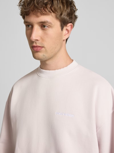 Männermodel trägt Oversized Sweatshirt mit Label-Stitching von Pegador aus Baumwoll-Mix, hellrosa mit Rundhalsausschnitt, Nahaufnahme Oberkörper.
