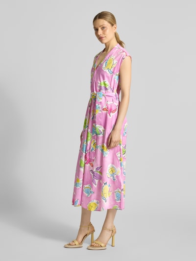 Modelka kobieca ma na sobie Midikleid mit V-Ausschnitt und Bindegürtel od Milano Italy, różowy kolor, motyw kwiatowy, czysta bawełna, krój A-linii, szerokość w rozmiarze 36: 50 cm, długość tyłu w rozmiarze 36: 127 cm, widok całej sylwetki z przodu