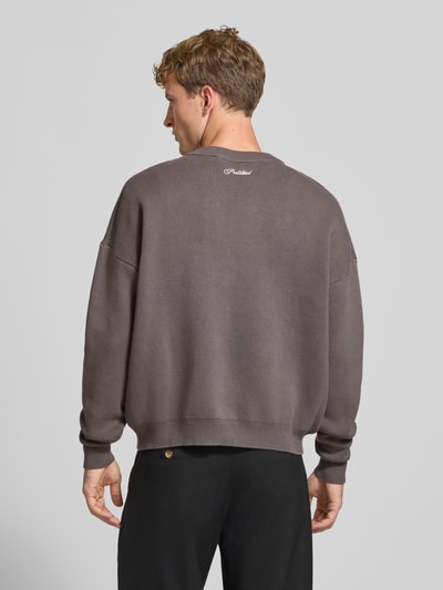 Mannermodel draagt Relaxed Fit gebreide pullover uit puur katoen van PROHIBITED in effen taupe met labelstitching, ribboorden, losse pasvorm, ruglengte maat M 64 cm, mouwlengte maat M 59 cm, Ganzkörperansicht Rückansicht.