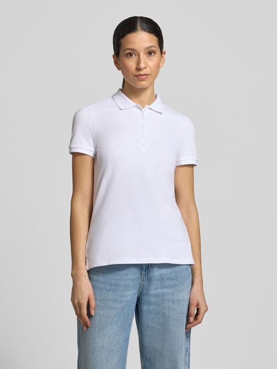 Frauenmodel trägt Slim Fit Poloshirt mit Knopfleiste von Christian Berg Woman aus Baumwoll-Elasthan-Mix, weiß, Seitenschlitze, Ganzkörperansicht von vorne. Rückenlänge bei Größe S: 62 cm.