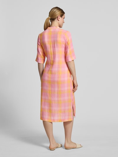 Frauenmodel trägt Relaxed Fit Midikleid mit Tunika-Kragen von Emily Van den Bergh aus Baumwoll-Mix in Rosa-Gelb mit Gelegte Falten, Halbarm, Ganzkörperansicht Rückansicht. Rückenlänge bei Größe 36: 112 cm, Brustweite: 48 cm, Ärmellänge: 36 cm.