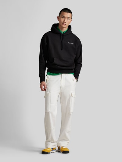 Mannelijk model draagt Relaxed Fit Hoodie aus Baumwoll-Mix van Polo Ralph Lauren in effen zwart met label print, sweatmateriaal, lange mouwen en kangoeroezak, uniseks, voorkant volledig zichtbaar.