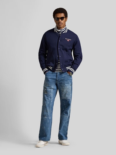 Männermodel trägt Regular Fit Blouson aus Baumwoll-Mix von Polo Ralph Lauren in Dunkelblau, College-Kragen, vorne unifarben, Ganzkörperansicht von vorne.