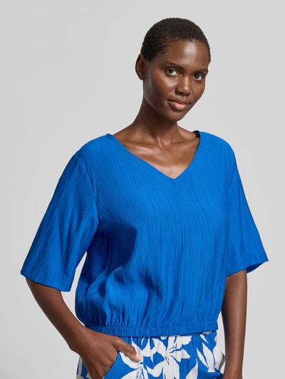Frauenmodel trägt Relaxed Fit Blusentop aus Viskose-Mix von s.Oliver RED LABEL in Blau mit Allover-Muster, floraler Satin, Nahaufnahme Oberkörper.