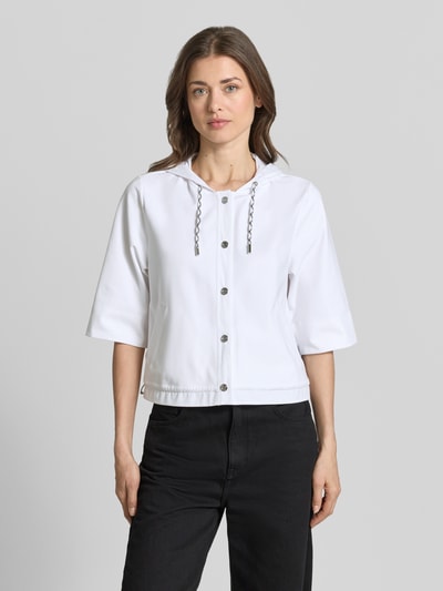 Frauenmodel trägt Regular Fit Jacke mit Kapuze von Marc Cain, weiß, Halbarm, Knopfleiste, Baumwoll-Mix, Ganzkörperansicht von vorne.