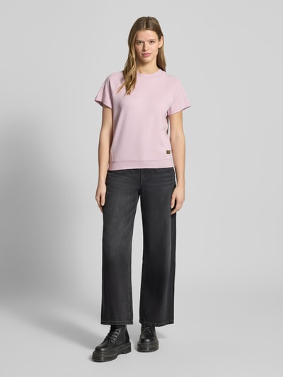 Kobiece model nosi Regular Fit T-Shirt mit Logo-Patch Modell 'Raglan' od G-Star Raw, bawełna, okrągły dekolt, krój regular fit, naszywka z logo, elastyczne wykończenie, długość tyłu w rozmiarze S: 57 cm, widok całej sylwetki z przodu.