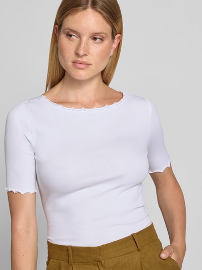 Kobiece model prezentuje t-shirt z okrągłym dekoltem i falistym wykończeniem od zero, Mieszanka bawełny z dodatkiem streczu, dopasowany krój, drobne prążkowanie, długość tyłu w rozmiarze 36: 51 cm, jasny kolor, prosty fason, gładka tekstura. Zbliżenie na górną część ciała z przodu.