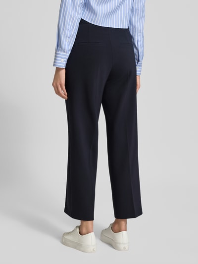 Männermodel trägt Straight Fit Stoffhose mit Ziernaht Modell 'Cameron' von Cambio, ciemnogranatowy kolor, elastyczny pas, kieszenie z tyłu, krój straight fit, długość skrócona, szerokość w rozmiarze 36: 39 cm, długość nogawki wewnętrznej: 67 cm, nadruk z logo, widok całej sylwetki z tyłu.