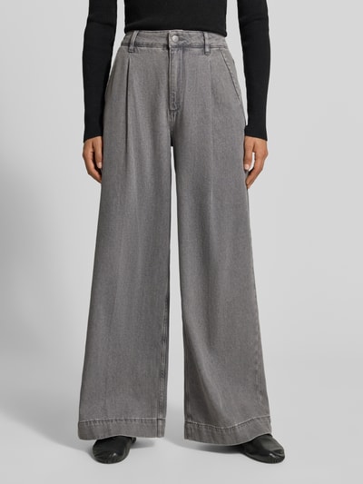 Frauenmodell trägt Wide Fit Jeans mit gelegten Falten von MYON aus reiner Baumwolle, grauer Farbton, Nahaufnahme Unterkörper.