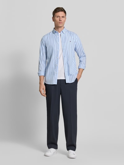 Männermodel trägt Regular Fit Freizeithemd aus reiner Baumwolle von Tommy Hilfiger, gestreift, blau-weiß, Popeline, Ganzkörperansicht von vorne.