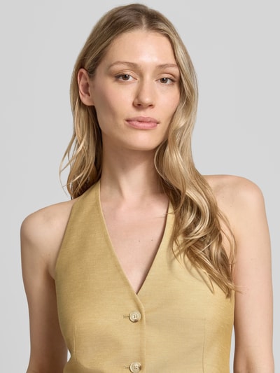 Frauenmodel trägt Weste mit Neckholder und V-Ausschnitt von Comma, Material-Mix mit Leinen-Anteil, Knopfleiste, Nahaufnahme Oberkörper.