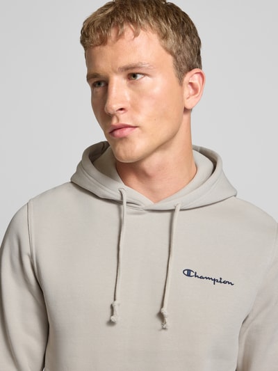 Männermodel trägt Hoodie mit Kapuze von CHAMPION aus Baumwoll-Mix, Label-Stitching, Tunnelzug, lockerer Schnitt, Nahaufnahme Oberkörper.