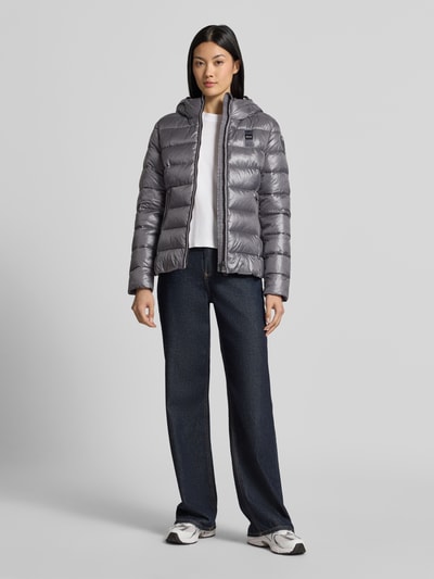 Frauenmodel trägt Jacke in Stepp-Optik Modell 'CAROLL' von Blauer USA in Anthrazit, glänzende Oberfläche, taillierte Form, Ganzkörperansicht von vorne.