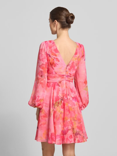 Frauenmodel trägt Cocktailkleid mit Ballonärmeln und V-Ausschnitt von Jake*s Cocktail in Pink mit floralen Mustern aus Chiffon, taillierter Schnitt, Minikleid, rückseitiger V-Ausschnitt und Rückenreißverschluss, Rückenlänge 91 cm, Brustweite 40 cm, Ärmellänge 65 cm, Ganzkörperansicht Rückansicht.