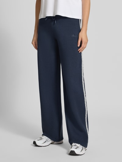 Kobiece model prezentuje Wide Fit Sweatpants aus Baumwoll-Mix od REVIEW, granatowy kolor, mieszanka bawełny, elastyczny pas, Bordiura, wyhaftowane logo, Długość wewnętrzna nogawki w rozmiarze S: 44 cm, Ganzkörperansicht z przodu.