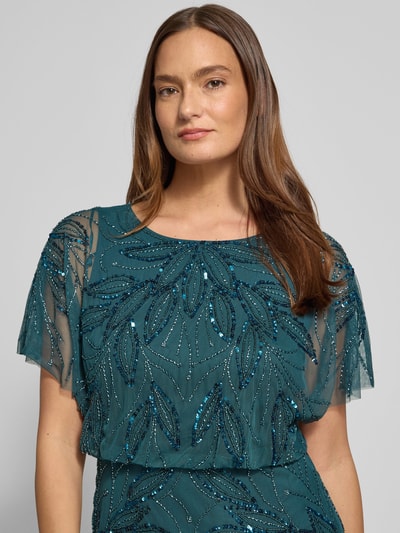Frauenmodel trägt Abendkleid mit Perlen und Pailletten von Christian Berg Cocktail in dunklem Türkis, transparenter Stoff, Nahaufnahme Oberkörper.