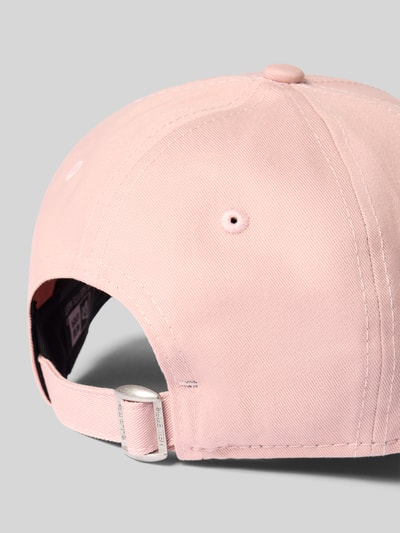 Produktfoto, Basecap aus reiner Baumwolle von New Era in zartem Rosa, verstärkter Schirm mit Steppnähten, verstellbarer Riegel auf der Rückseite, Motiv-Applikation, glatte Oberfläche