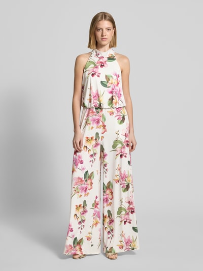 Modelka nosi Regular Fit Jumpsuit mit floralem Allover-Print von V by Vera Mont, białe tło, kolorowy kwiatowy wzór, krój regular fit, bez rękawów, wycięcie na plecach, zamek w szwie, długość tyłu w rozmiarze 36: 147 cm, szerokość w rozmiarze 36: 36 cm, całkowita długość w rozmiarze 36: 132 cm, długość wewnętrzna nogawki w rozmiarze 36: 81 cm, widok całej sylwetki z przodu.