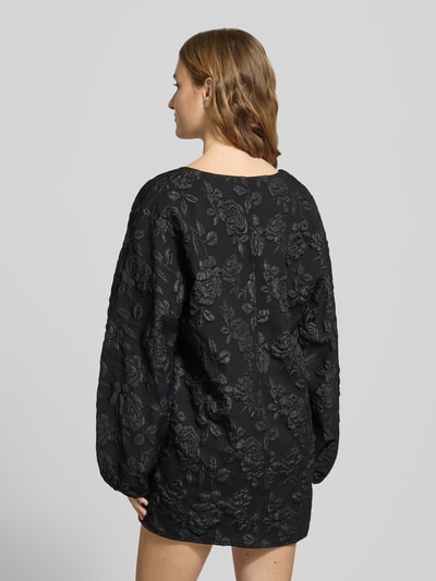 Vrouwenmodel draagt Minikleid mit V-Ausschnitt van Gina Tricot, zwarte kleur, losse fit, reliëfstructuur, rugaanzicht full body.