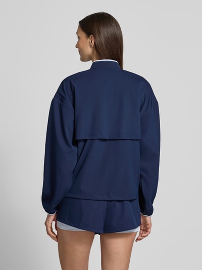 Frauenmodel trägt Regular Fit Trainingsjacke mit Baseball-Kragen von Lacoste Sport, unifarben dunkelblau, Ganzkörperansicht Rückansicht.