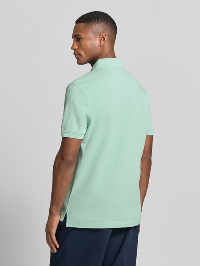 Mężczyznamodel nosi Regular Fit Poloshirt aus Baumwoll-Mix od Tommy Hilfiger, kolor jednolity, krój regular fit, logo, bawełniany piqué, całkowity widok z tyłu.