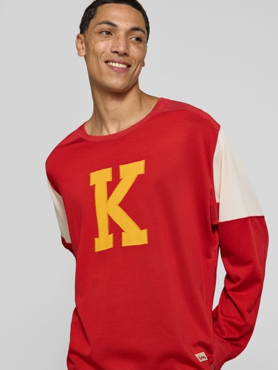 Männermodel trägt Relaxed Fit Longsleeve aus viscosemix van Kenzo in rood met geel labelstitching, ronde hals, elastische mouwen, ruglengte bij maat M 73 cm. Nahaufnahme Oberkörper.