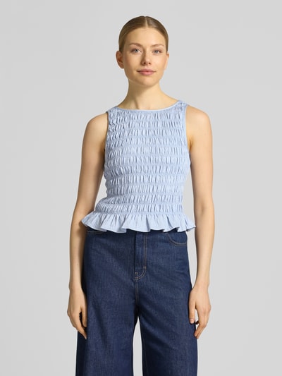 Frauenmodel trägt Slim Fit T-Shirt aus Viskose-Mix Modell 'NORI SMOCK' von Vero Moda in Hellblau, strukturiert, ärmellos, Raffung, Ganzkörperansicht von vorne.