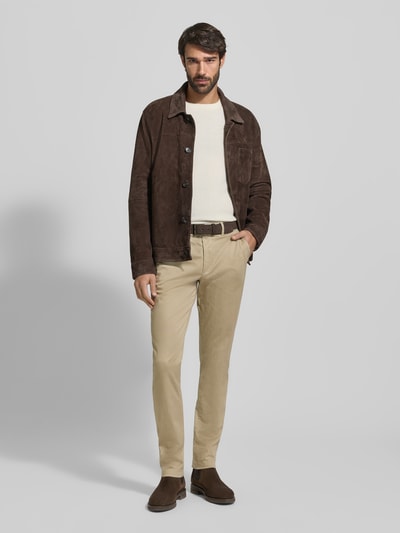 Männermodel trägt Slim Fit Chino aus Baumwoll-Mix Modell 'BLEECKER' von Tommy Hilfiger in Beige, unifarben, Ganzkörperansicht von vorne.