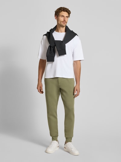 Männermodel trägt Regular Fit Sweathose aus Baumwoll-Mix von Polo Ralph Lauren, Olivgrün, kombiniert mit weißem T-Shirt, Ganzkörperansicht von vorne, Herren Sweathose von Polo Ralph Lauren.