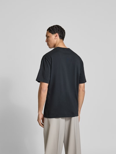 Männermodel trägt Regular Fit T-Shirt aus reiner Baumwolle von Closed in Schwarz mit Used-Look, Label-Print, Rückenlänge 76 cm, Ganzkörperansicht Rückansicht.