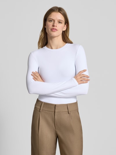 Modelka nosi Slim Fit Langarmshirt mit Rundhalsausschnitt Modell 'LULA' od Pieces, biały kolor, gładka rozciągliwa struktura, krój slim fit, widok całej sylwetki z przodu.