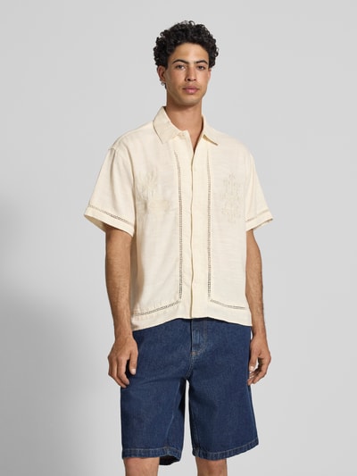 Männermodel trägt Relaxed Fit Freizeithemd aus Lyocell-Mix Modell 'Menton' von Jack & Jones, beige, florales Loch-Stitching, Kentkragen, Kurzarm, durchgehende Knopfleiste, Baumwoll-Lyocell-Mix, lockere Passform, Ganzkörperansicht von vorne.