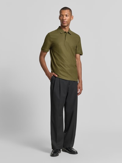 Männermodel trägt Regular Fit Poloshirt aus reiner Baumwolle Modell 'Parley 321' von BOSS in Olivgrün, strukturierte Textur, Ganzkörperansicht von vorne, Herren Poloshirt von BOSS.
