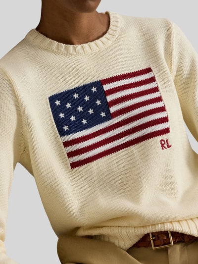 Frauenmodel trägt Strickpullover mit Flaggen-Motiv und Rundhalsausschnitt von Polo Ralph Lauren in Creme, reine Baumwolle, Nahaufnahme Oberkörper.