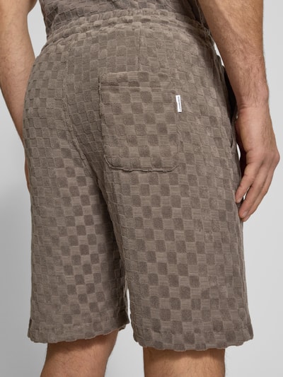Mężczyznamodel nosi Regular Fit Shorts mit Label-Patch od Lindbergh, bawełniany miks, kieszeń tylna, tekstura w kratę, szerokość w rozmiarze M: 45 cm, długość wewnętrzna nogawki: 22 cm, ujęcie całego ciała z tyłu.