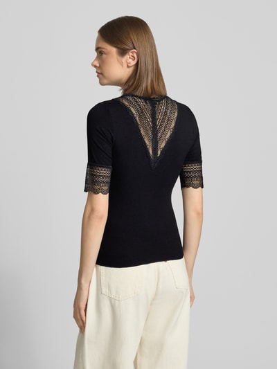 Vrouwenmodel draagt Slim Fit T-Shirt uit viscosemix model 'Tilde' van Only, zwart, kantdetails, fijnrib structuur, achterkant totaalbeeld.