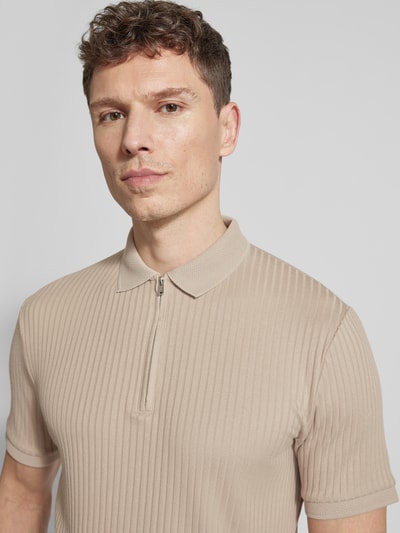 Männermodel trägt Regular Fit Poloshirt mit Bio-Baumwoll-Anteil Modell 'FAVE' von SELECTED HOMME in Beige, Rippstruktur, Nahaufnahme Oberkörper.