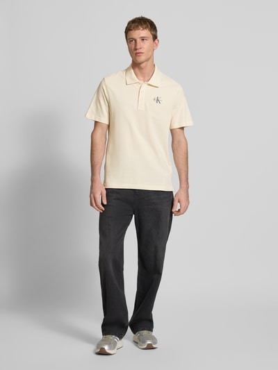 Männermodel trägt Easy Fit Poloshirt mit Polokragen von Calvin Klein Jeans aus reiner Baumwolle mit Label-Stitching, Ganzkörperansicht von vorne.