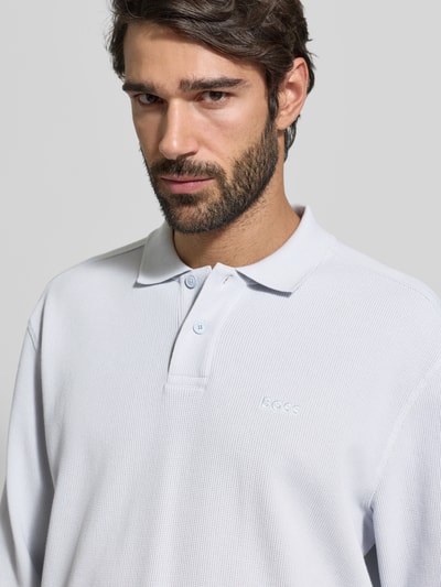 Männermodel trägt Regular Fit Poloshirt aus Baumwoll-Mix Modell 'PETEMPESTOLONG' von BOSS Orange, Optik: Unifarben, Nahaufnahme Oberkörper.